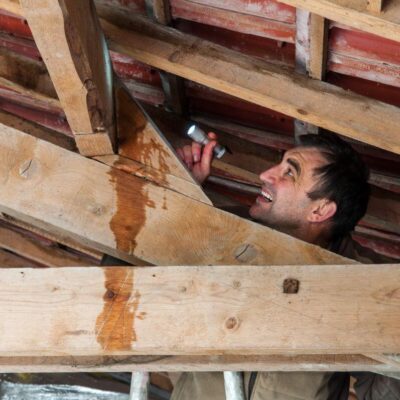 Mężczyzna podczas inspekcji z latarką to typowa scena przy naprawie dachów.