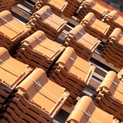 Stosy dachówek ceramicznych ułożone na paletach.