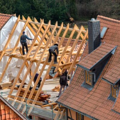 Robotnicy pracują przy budowie dachu, na którym zostaną zainstalowane dachówki ceramiczne.
