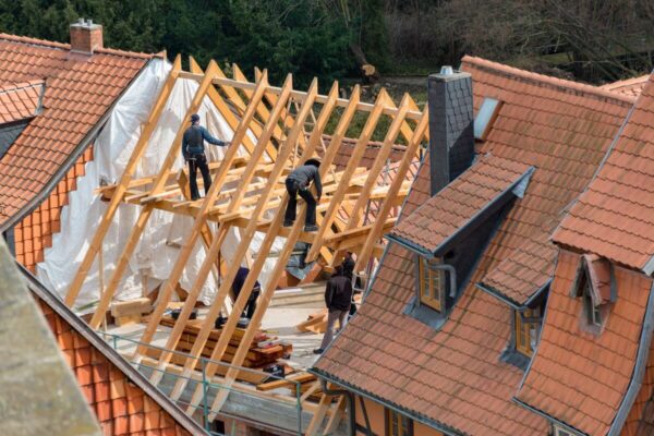 Robotnicy pracują przy budowie dachu, na którym zostaną zainstalowane dachówki ceramiczne.