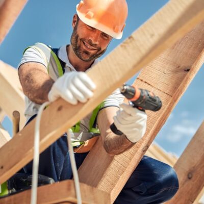 Certyfikowany dekarz pracuje na dachu, używając wiertarki.